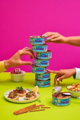 Hände die Jenga aus Dosen von Betta Fish spielen angeordnet auf einem Tisch fotografiert von Werbefotografen Silly berlin. 